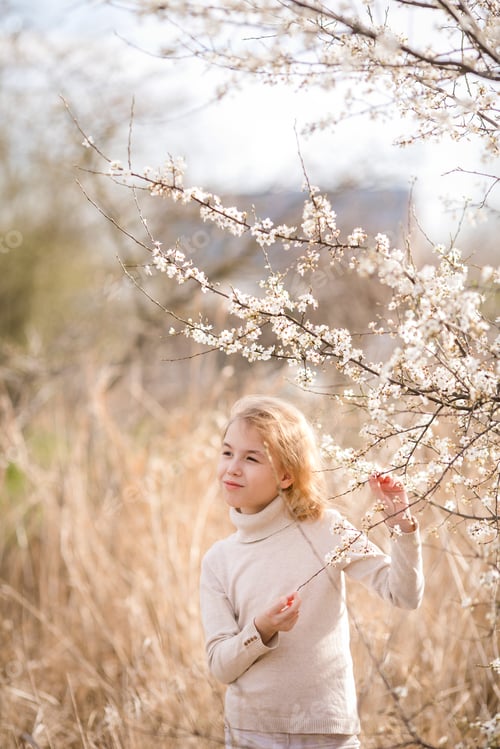 Preview: Blonde girl in the blossom garden. Spring background with white flower
