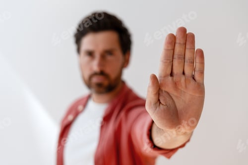 Preview: Serious handsome Latin man making stop gesture with open hand selective focus, closeup