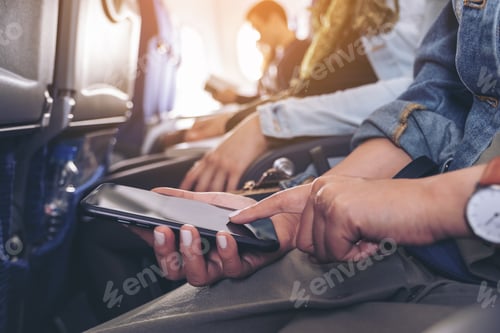 Preview: a woman holding and touching at a black smart phone screen while sitting in the cabin