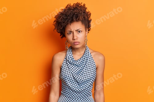 Vista previa: Portrait of displeased offended dark skinned woman looks with disappointed expression wears earrings