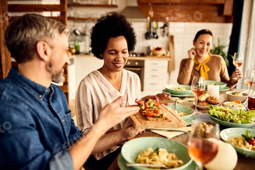 Preview: Smiling African American woman enjoying in lunch with her friends at home.