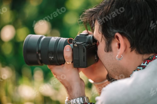 Preview: Man photographer taking photos on professional digital camera outdoors. Cameraman working with DSLR