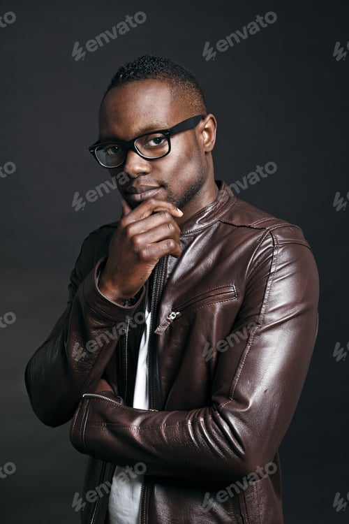 Preview: Confident Casual Young Black Man Wearing Brown Leather Jacket And Glasses. Studio Portrait Against