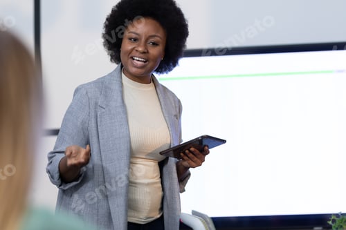 Preview: African american businesswoman holding digital tablet and giving presentation to business colleagues