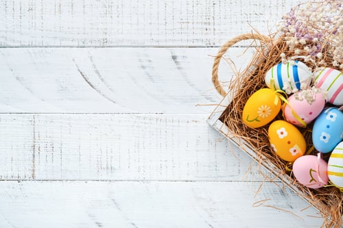 Preview: Easter holiday. Colorful Easter eggs in wooden basket on white wooden background. Easter greeting ca