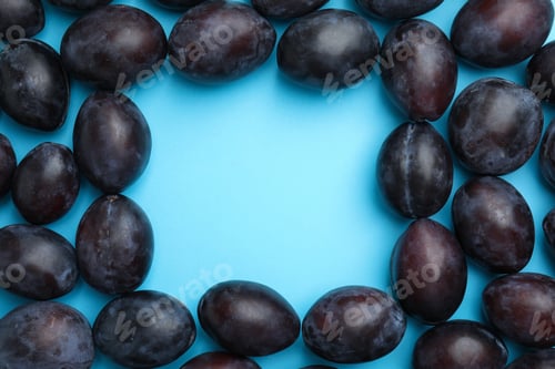 Preview: Frame made of delicious ripe plums on light blue background, flat lay. Space for text