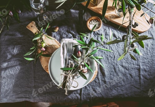 Preview: Top view of table setting with gray Linen tablecloth and napkin, white plate, cutlery and and olive