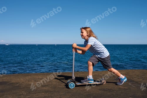 Preview: Boy riding a scooter on a pier at sunny day