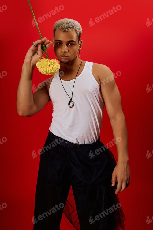Preview: Young man with dyed hair showcases trendy style in vibrant red studio setting