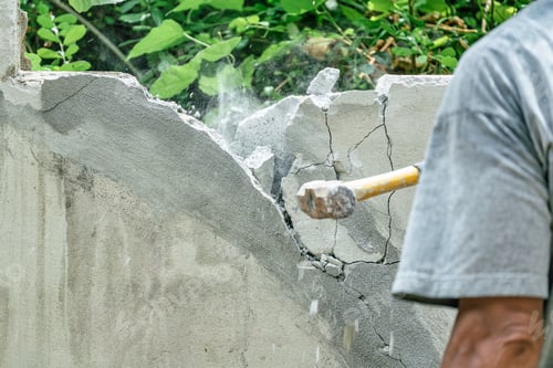Preview: Hand of worker using hammer smashing and demolish on brick wall at construction site