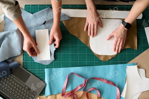 Preview: Overview of hands of two female tanners with sewing paper patterns