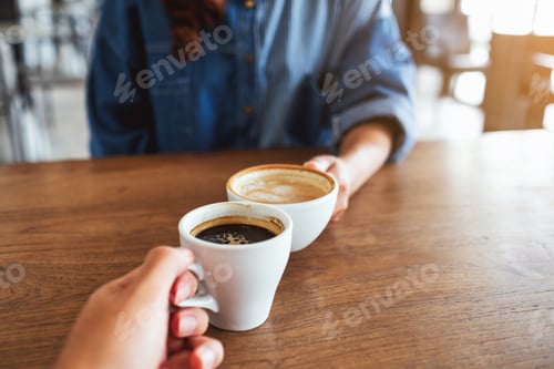 Preview: Closeup image of a woman and a man clinking coffee cups together in cafe