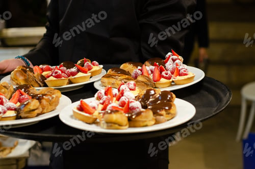 Preview: Waiter serving sweet pastries with chocolate, strawberries, and raspberries on white plates