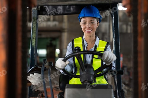 Preview: Smiling African American female worker driving forklift truck in heavy metal industrial factory
