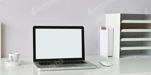 Preview: A white blank screen computer laptop is putting on a white workspace surrounded by office equipment.