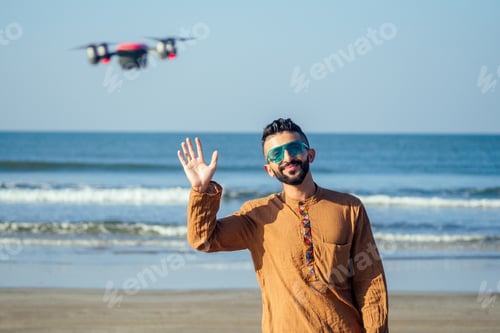 Preview: Drone remote control. Arabian man operating copter controller contactless by hands by sea