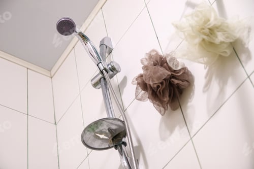 Preview: A silver shower head and a white washcloth on clean tiles in a modern bathroom