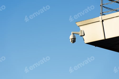 Preview: close up view of security camera on building facade with clear blue sky