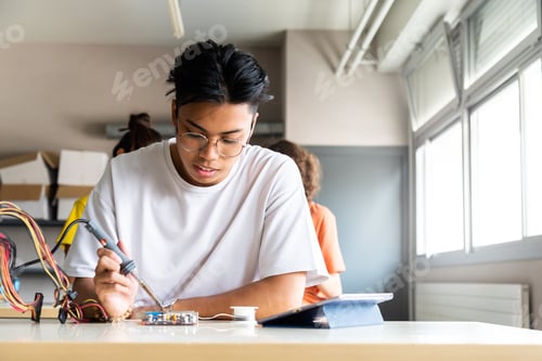 Preview: Teen asian boy high school student in class learning electronics . Copy space. Education concept.