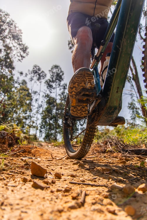 Preview: Senior cyclist pedaling his electric mountain bike uphill on a dirt path