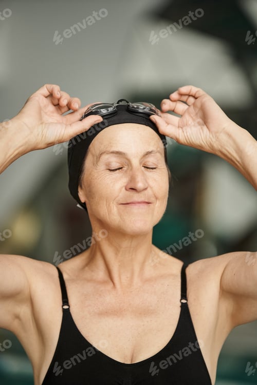 Preview: portrait, active lifestyle, mature woman in swimwear, adjusting goggles, swim cap, spa center