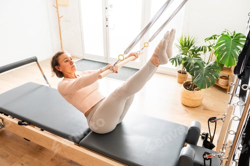 Preview: Woman exercising pilates using reformer in studio