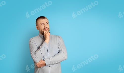 Preview: Thoughtful Middle Aged Man Thinking Touching Chin On Blue Background