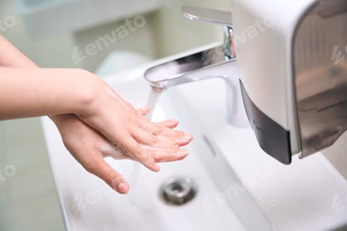 Preview: Patient washes his soapy hands under the tap