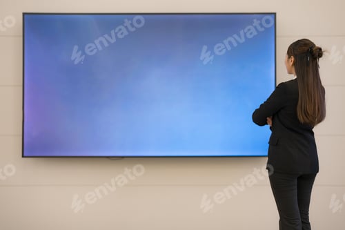 Preview: Young businesswoman analyzing data on large screen