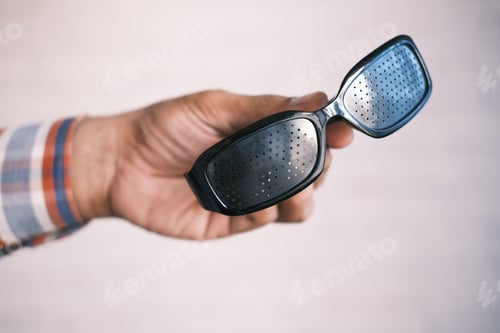 Preview: holding a Perforation glasses with holes for training vision