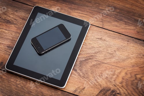 Preview: Multifunctional gadgets. Close-up of digital tablet with mobile phone laying on the wooden desk