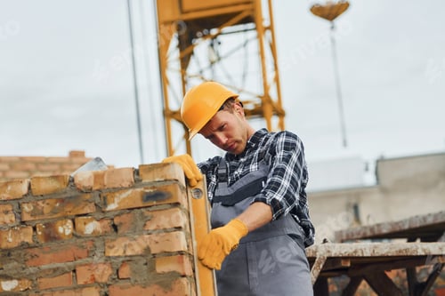 Preview: With level measuring tool. Construction worker in uniform and safety equipment have job on building