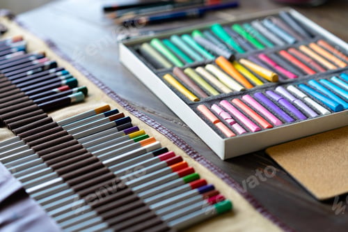 Preview: color pencils and pastel crayons on wooden table. art painter accessories. daylight.