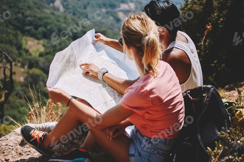 Preview: Traveling man and woman studying map on hill