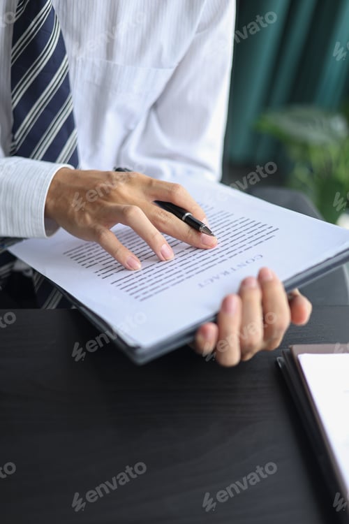 Preview: Male executive singing legal documents for a corporate partnership at desk.