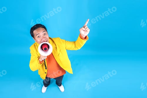 Preview: Funny Asian Guy in Vibrant Style Shouting on Megaphone While Pointing to Aside