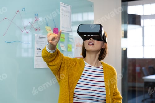 Preview: Asian businesswoman standing in front of whiteboard wearing virtual reality headset