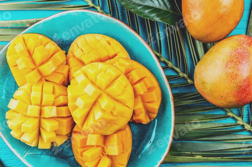 Preview: Mango on blue plate. Blue background, palm tree leave, tropical concept