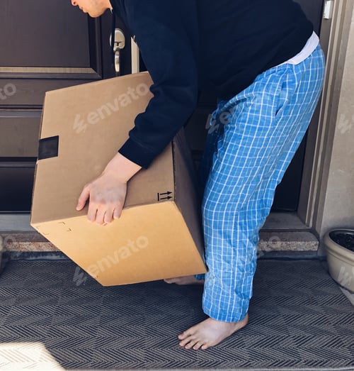 Preview: Young man in his pajamas picking up a large parcel on the front porch of a house