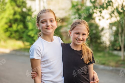 Preview: Two tween girls smiling and posing together while enjoying sunny outdoor moment