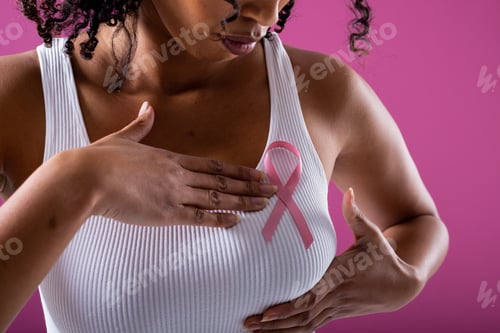 Preview: Midsection of african american mid adult woman with pink breast cancer awareness ribbon on breast