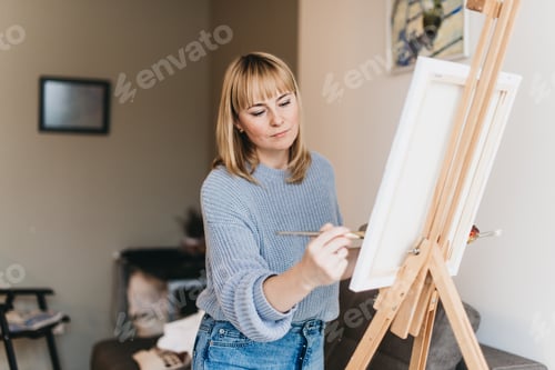 Preview: Young woman artist painting a picture in studio