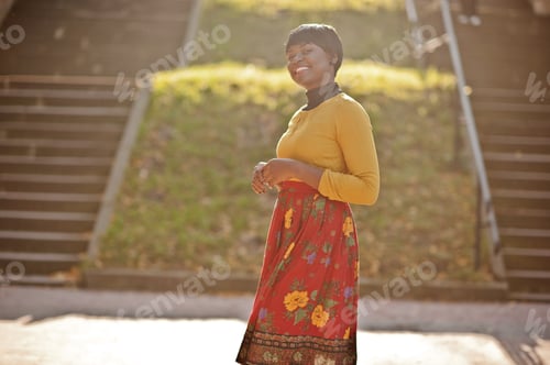 Preview: African american girl at yellow and red dress at golden autumn fall park.