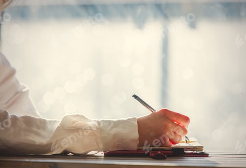 Preview: hand with pen writing something in to a notebook