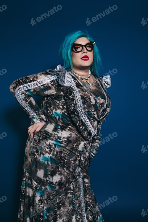 Preview: A confident queer individual showcases unique fashion against a vibrant blue backdrop