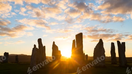 Preview: Ancient standing stone formation at sunset under a cloudy sky.