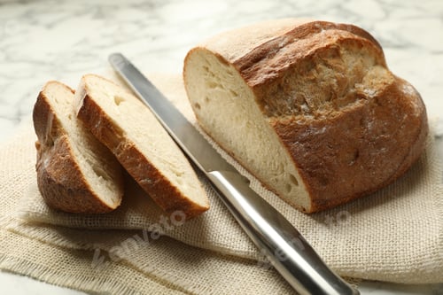 Preview: Pieces of fresh bread and knife on table, closeup