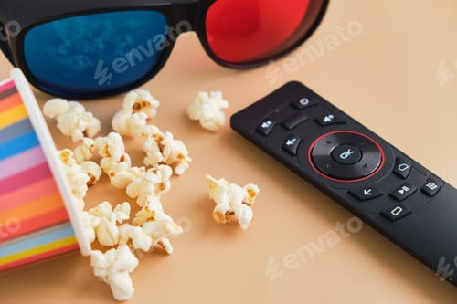 Preview: Bowl of popcorn, 3d glasses, tv remote on beige background. Leisure and entertainment concept.