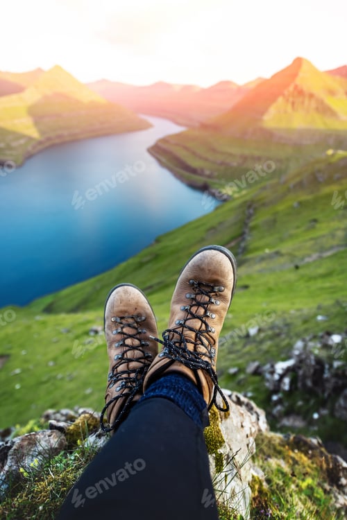 Preview: Boots of lonely tourist over majestic fjords of Funningur