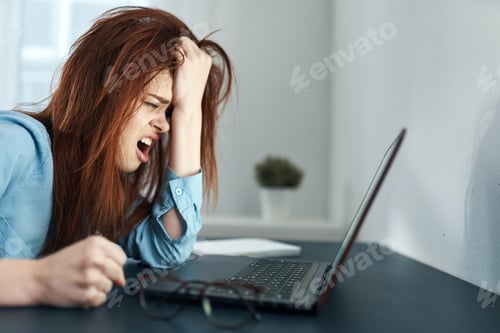 Preview: tired woman sitting at a table in front of a laptop work dissatisfaction